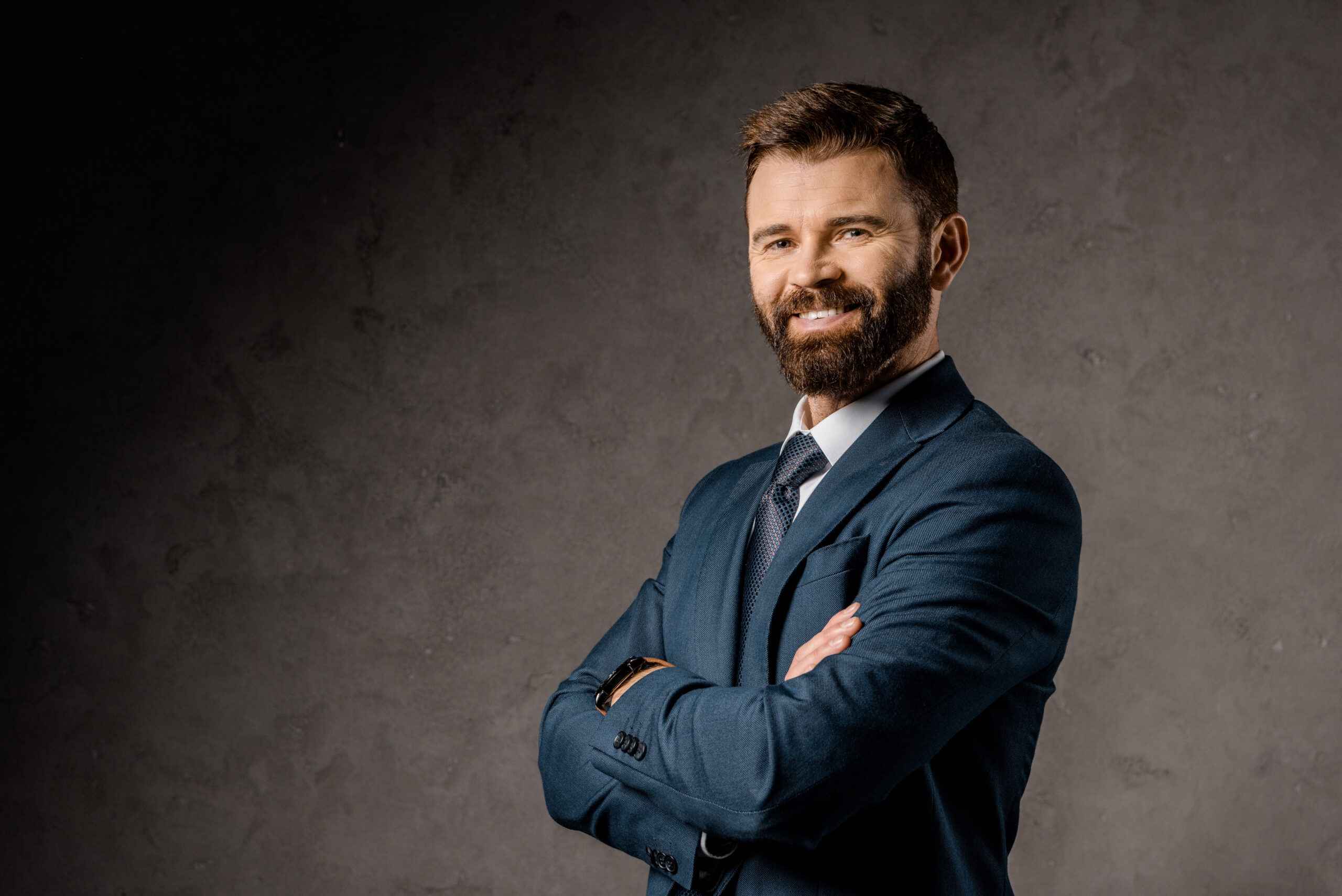 smiling bearded businessman standing with crossed arms